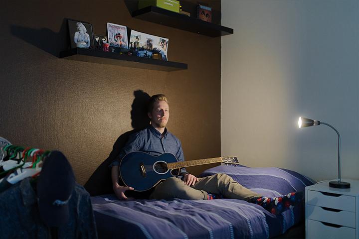 Tatu Helle sängyllä kitara sylissä.